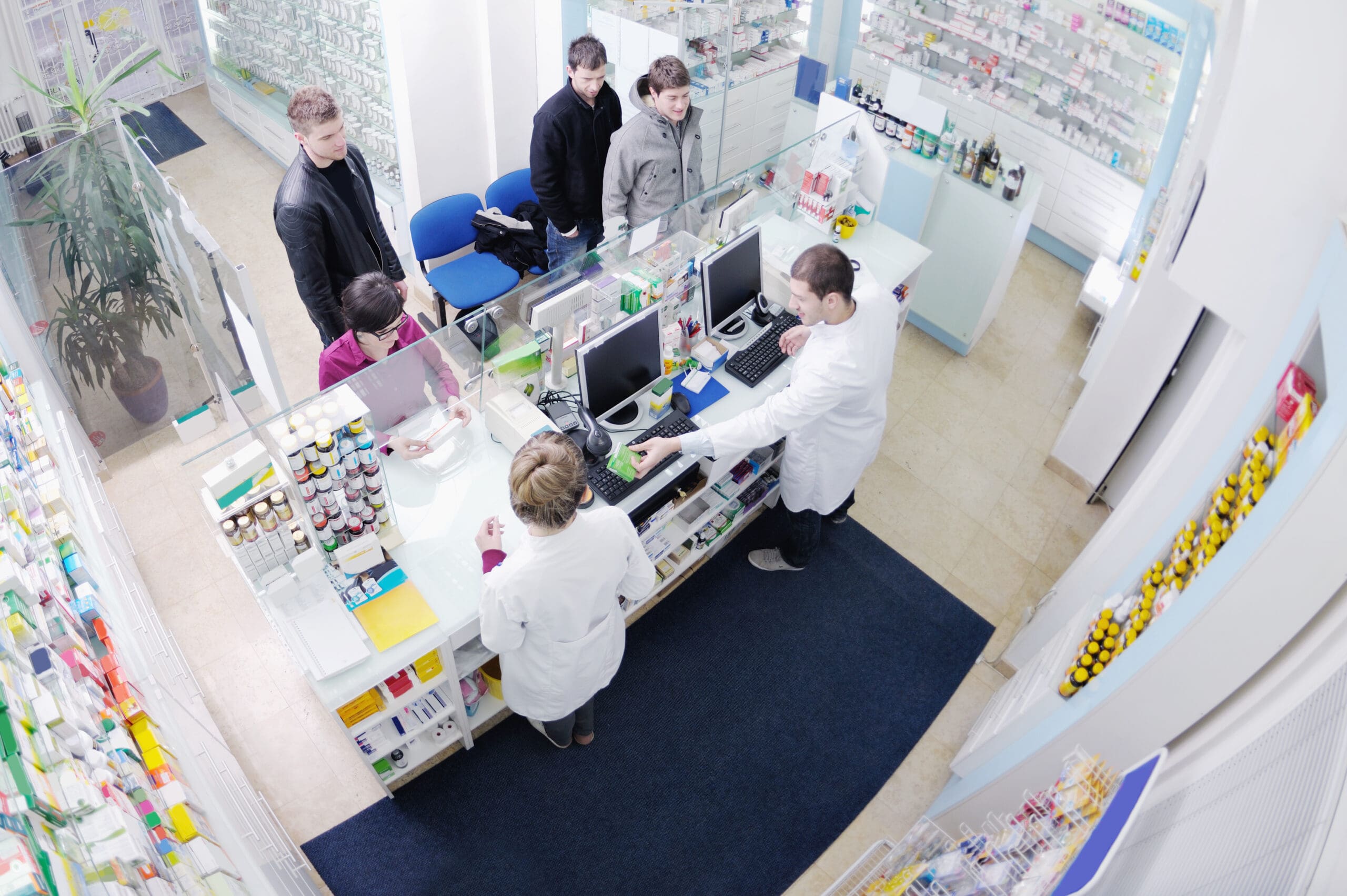 a group of people standing around a counter in a pharmacy