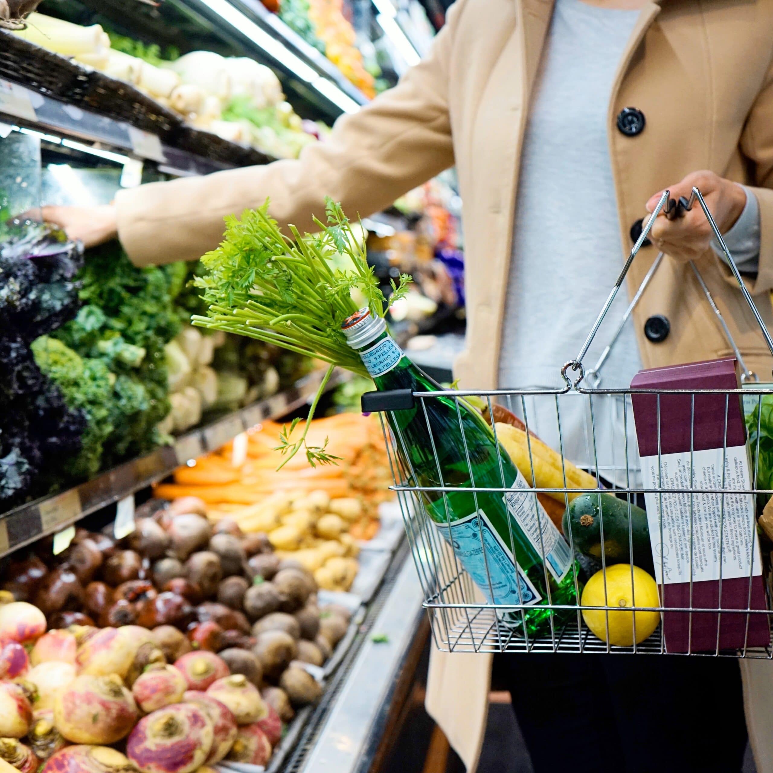 woman putting items in her cart from the produce aisle